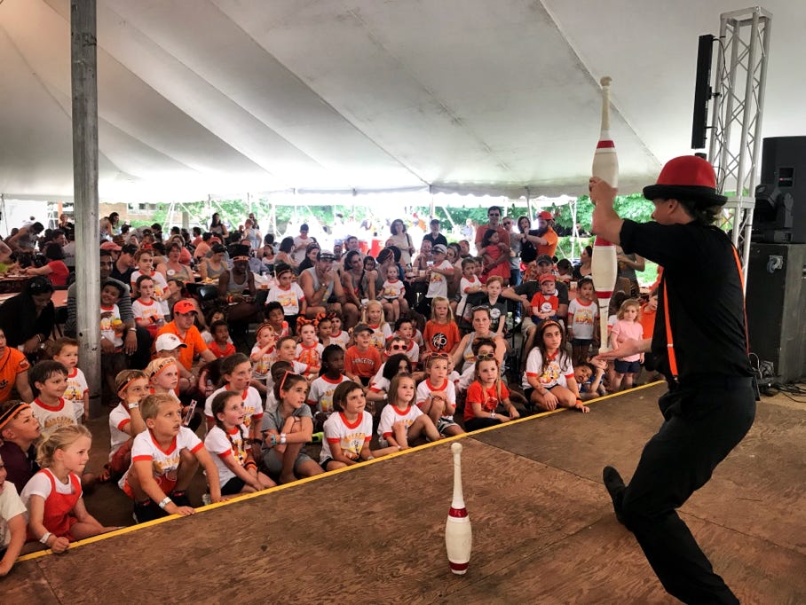 juggler balancing clubs in front of a large audience