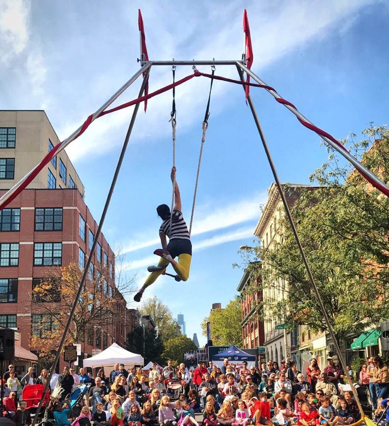 trapeze performer at outdoor festival with large audience