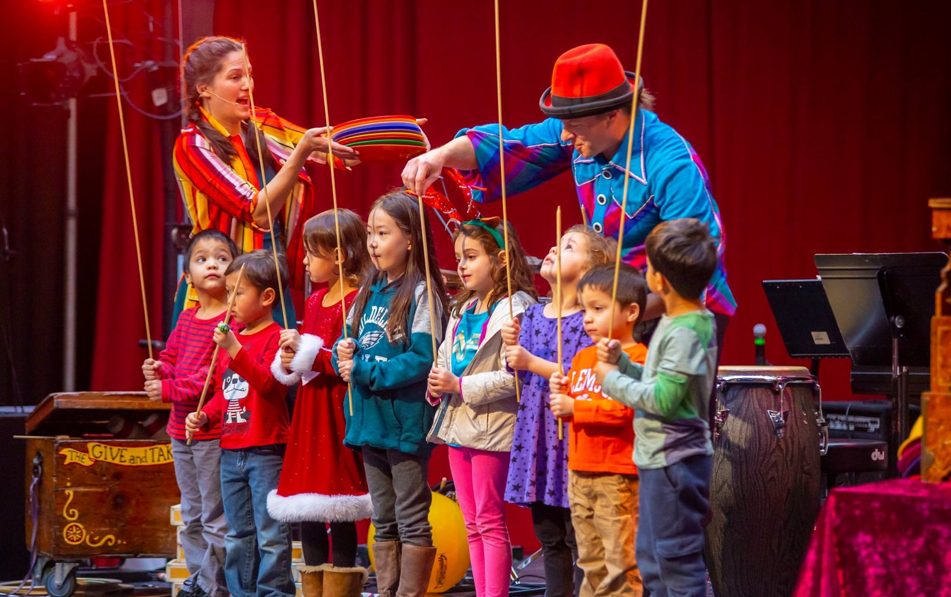 colorfully dressed children holding spinning plate sticks onstage