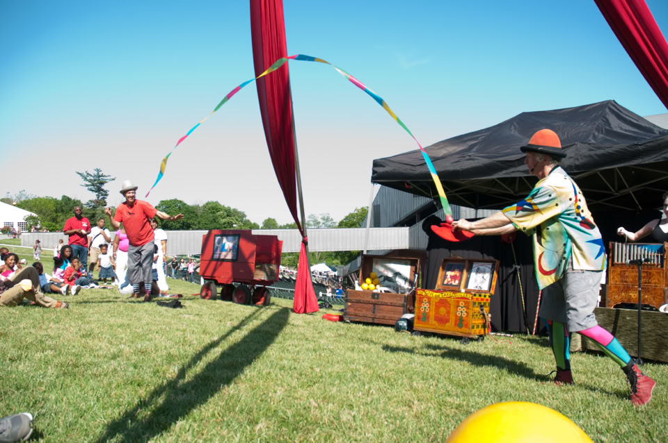 2 performers throwing a colorful ribbon into a hat