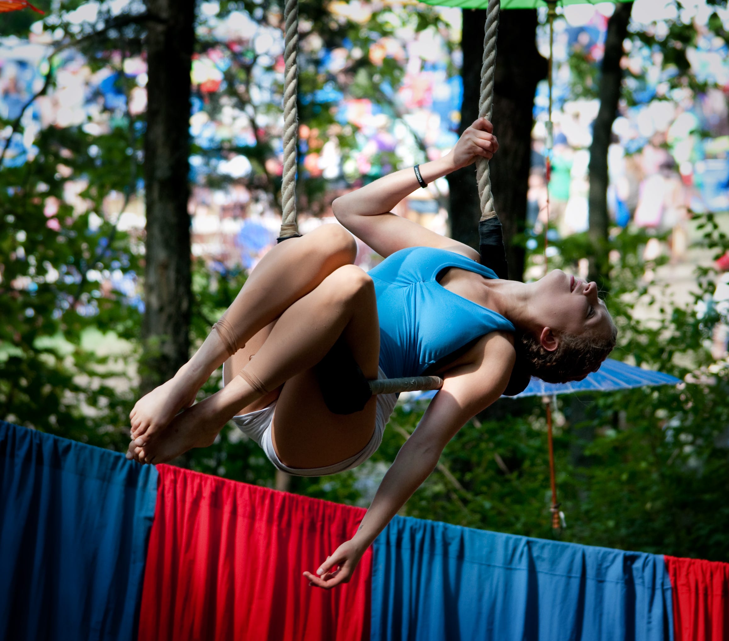 circus aerialist hanging sideways on a trapeze at a festival