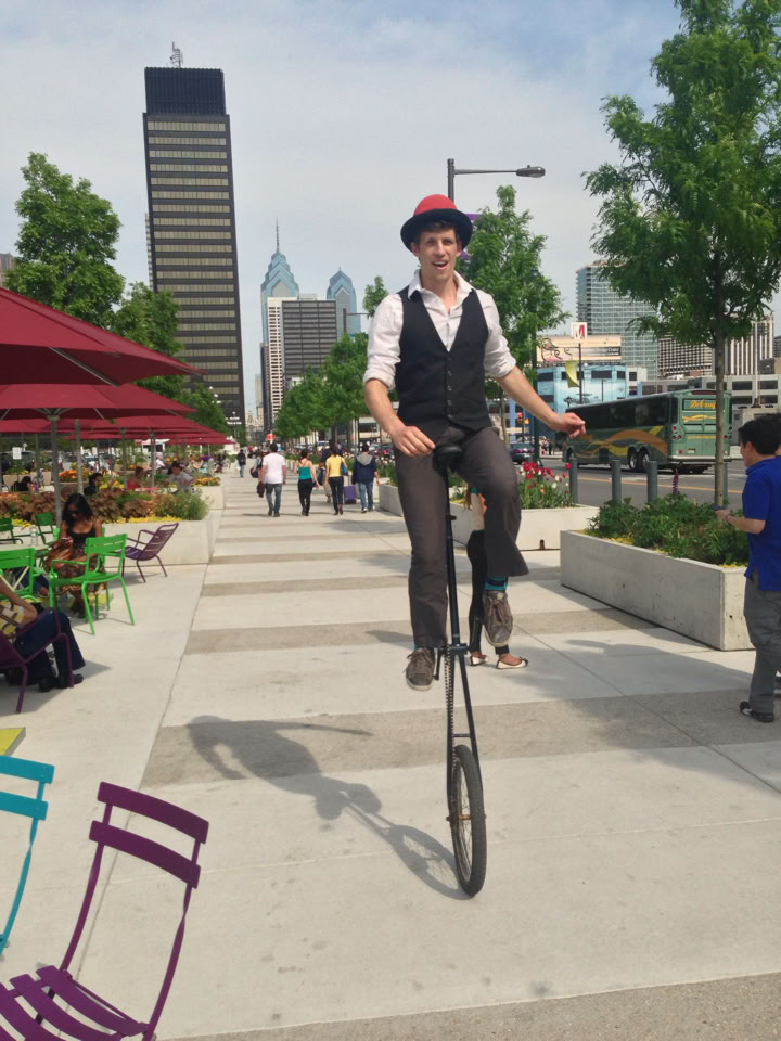 tall giraffe unicycle riding down the sidewalk
