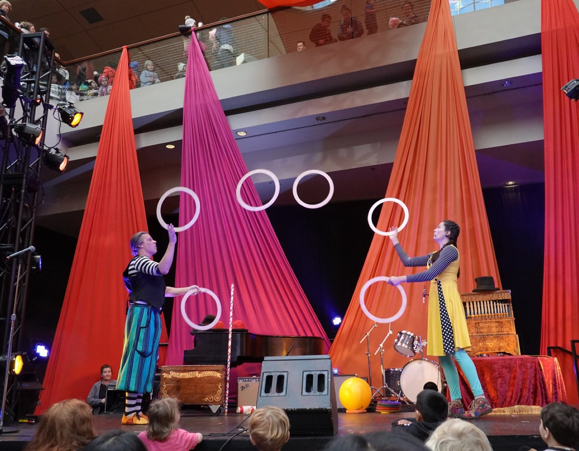 2 jugglers passing 6 rings on a decorated stage