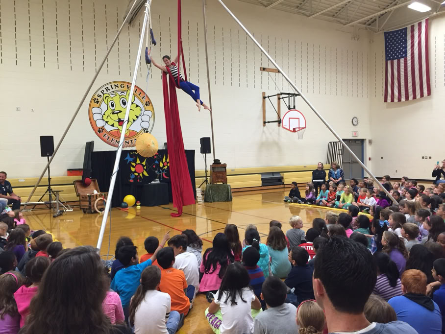 students in gym watching circus aerialist