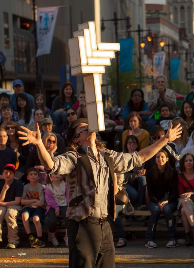 dramatic light on cigar box balncer in a street fair